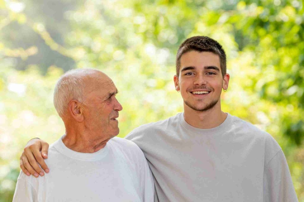 Elderly man smiling with a young man outdoors