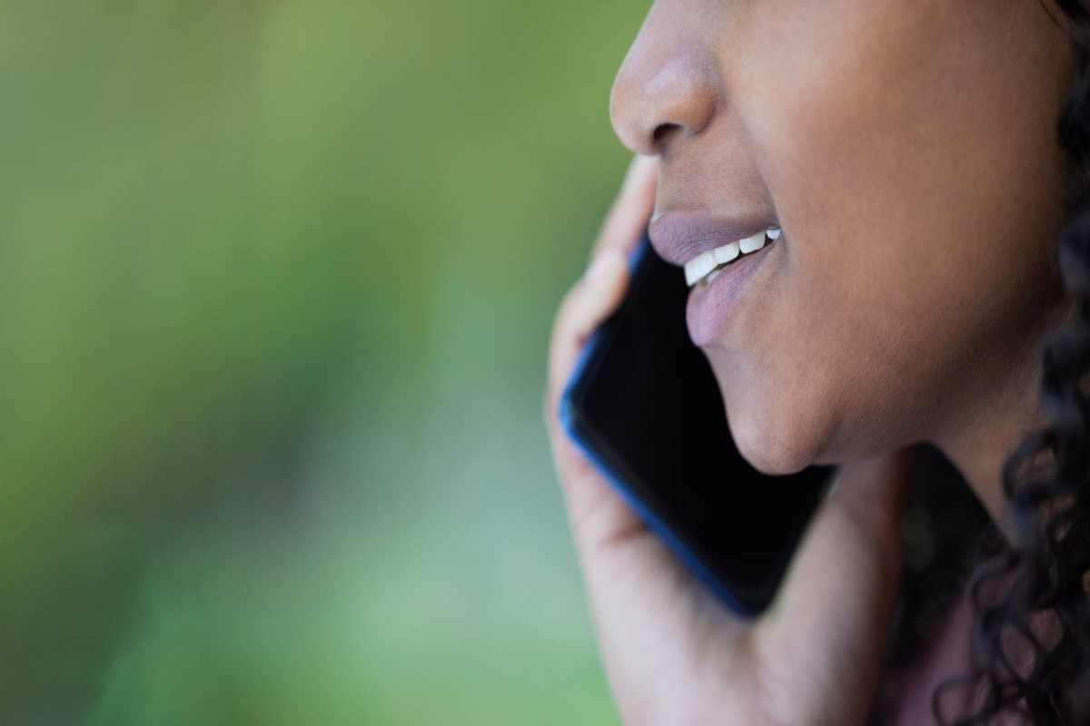 Close-up of a woman holding a smartphone to her ear while speaking