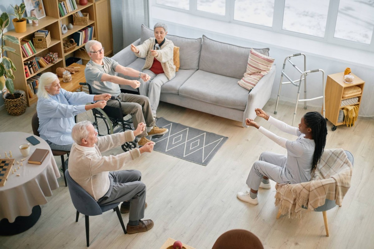Seniors doing gentle seated exercises with an instructor in a care home