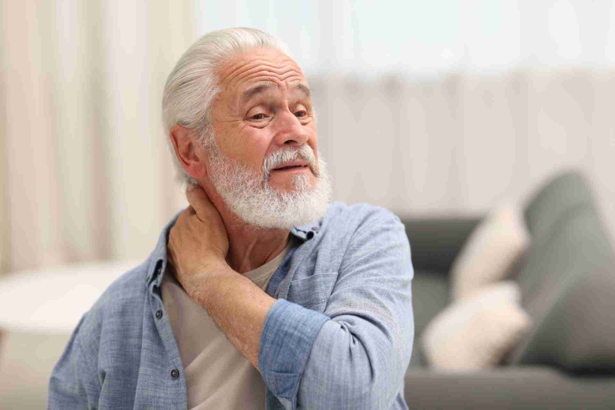 Older man touching his neck with a pained expression

