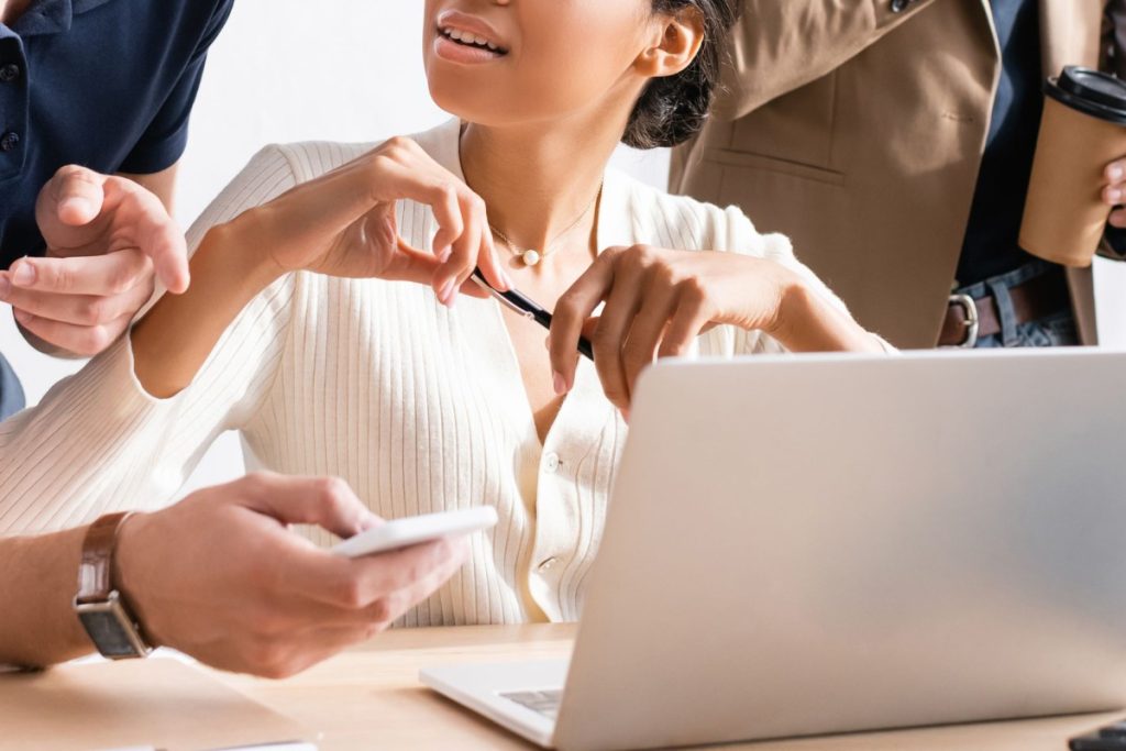 Close-up of colleagues collaborating around a laptop.Close-up of colleagues collaborating around a laptop.